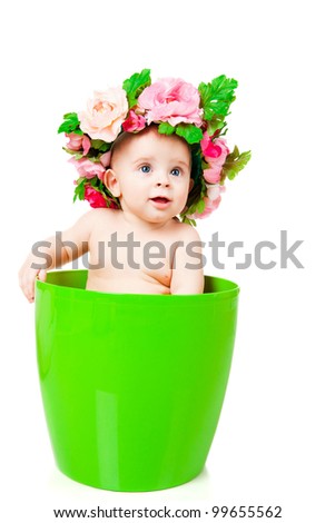 baby in a wreath sits in a flower pot