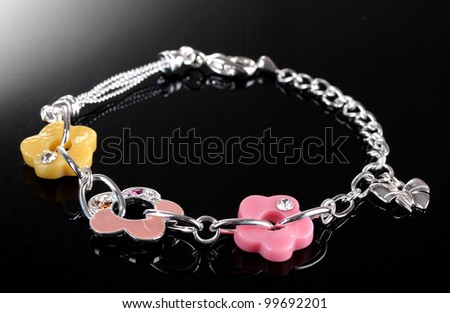 Beautiful silver bracelet with bright flowetrs on grey background