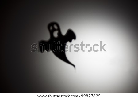A scary ghost shadow flying against an illuminated white background