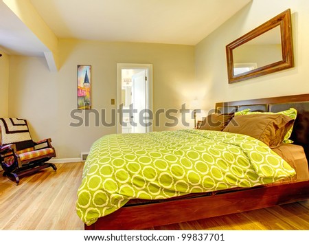 Modern bedroom with bright green bed spread and hardwood floor.
