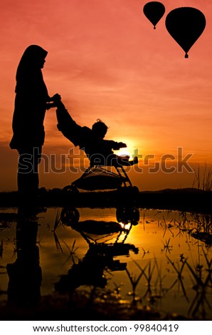 Mother and son walking at park during sunset