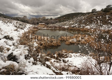 Landscape picture of a reservoir in the desert with snow and clouds
