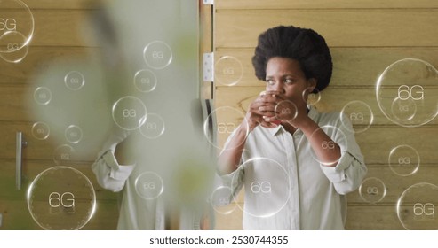 Image of 6g text over african american woman drinking coffee. Global social media, networks, digital interface and data processing concept digitally generated image.