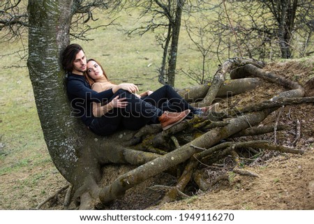 Image of adorable brunette couple in love sitting on the tree roofs in forest . Happy family. Couple with long beautiful hair and clear skin.