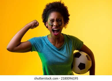 Image Of African American Female Soccer Fan With Flag Of Portugal Cheering In Yellow Lighting. Sport, Fans, Cheering And Emotions Concept.