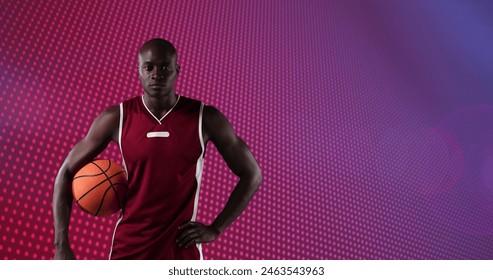 Image of african american male basketball player holding ball over red pixels with moving light. pro sports template concept with copy space, digitally generated image. - Powered by Shutterstock