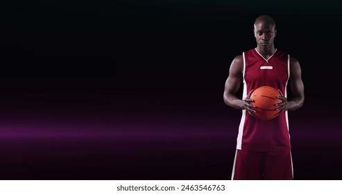 Image of african american male basketball player holding ball on dark background with pink light. pro sports template concept with copy space, digitally generated image. - Powered by Shutterstock