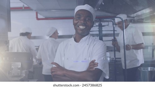 Image of african american male chef smiling in kitchen over light spots. labor day and celebration concept digitally generated image. - Powered by Shutterstock