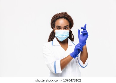 Image of african american nurse or doctor woman wearing medical face mask wearing disposable gloves isolated against white background