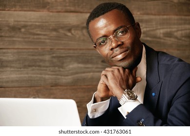 Image Of African American Student Of Law Working On Laptop Computer, Using High-internet Connection While Sitting At The Cafe Against Wooden Wall Background. Handsome Smiling Young Black Man