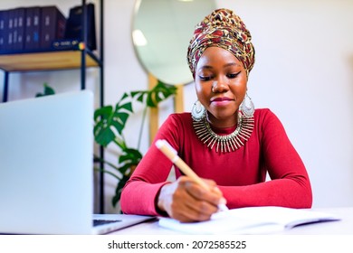 Image Of African American Woman With Turban Over Head Using Laptop In Office