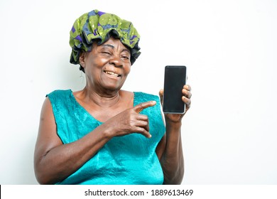 image of african old woman pointing finger on smart phone, indoor portrait of black aged mother with head wrap, holding telephone- studio communication concept