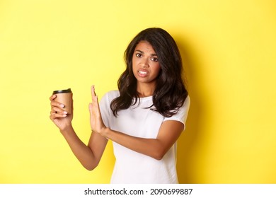 Image Of African-american Girl Complaining About Bad Taste Of Coffee, Showing Reject Sign And Pulling Away Cup, Standing Over Yellow Background