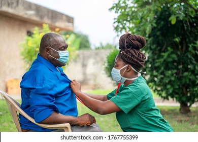 image of an aged African man being checking up by a health worker-young black nurse wearing a face mask taking care of an old man- health worker at home service