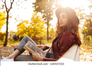공원에서 책을 읽으면서 벤치에 앉아 있는 한 놀라운 아름다운 여인의 이미지. 스톡 사진