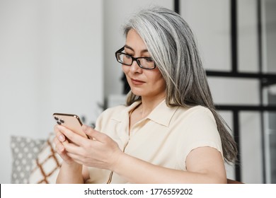 Image Of Amazing Mature Pleased Business Woman Designer Indoors At Home Using Mobile Phone.