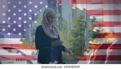 Image of American flag waving with jigsaw puzzles revealing biracial woman in hijab using smartphone and checking time in the background. American society diversity concept digital composition. - Powered by Shutterstock