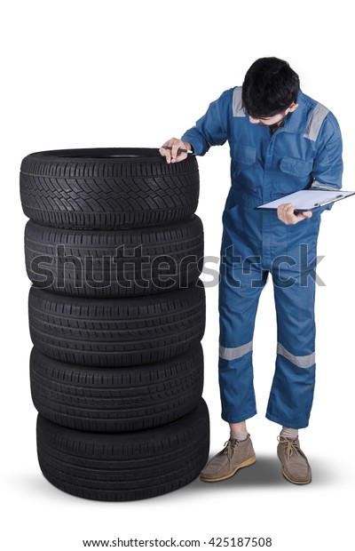 Image of Arabic\
mechanic wearing uniform and checking the texture of tires,\
isolated on white\
background