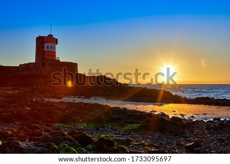 Image of Archirondel beach at low tide with the Jersey Tower shore at sunrise with a clear sky, Jersey Channel Islands 