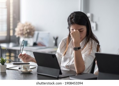Image of an Asian business woman is stressed, bored, and overthinking from working on a tablet at the office.