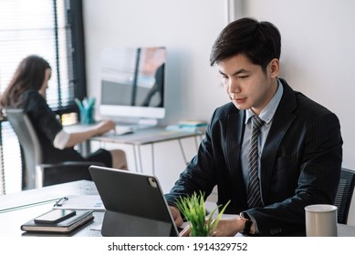 Image Of An Asian Businessman Studying And Analyzing Work Using A Tablet At The Office.