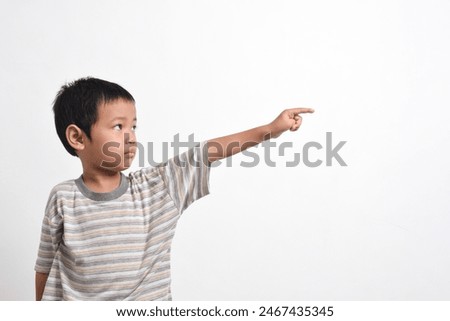 Image of Asian child posing scared and sad pointing towards the side on a white background. portrait of an Asian boy