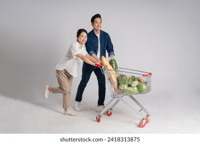 Image of Asian couple pushing supermarket cart while shopping, isolated on white background - Powered by Shutterstock