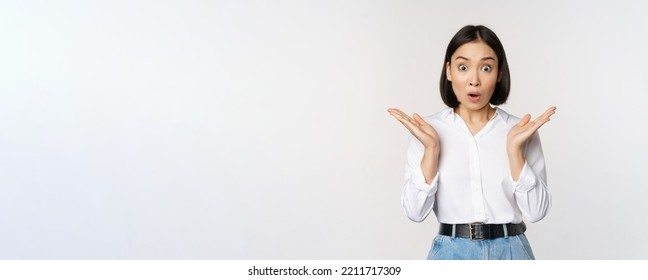 Image Of Asian Female Model Looking Surprised, Staring Amazed, Reacting At Surprise Big News, Standing Over White Background