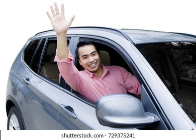 Image Of Asian Man Driving A New Car While Waving Hands At The Camera, Isolated On White Background