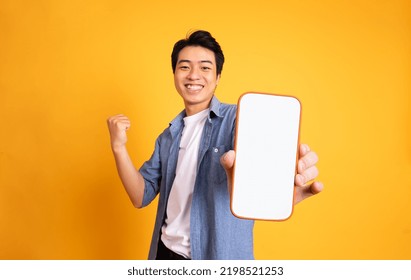 image of asian man holding phone, isolated on yellow background - Shutterstock ID 2198521253