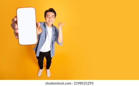 image of asian man holding phone, isolated on yellow background - Shutterstock ID 2198521295