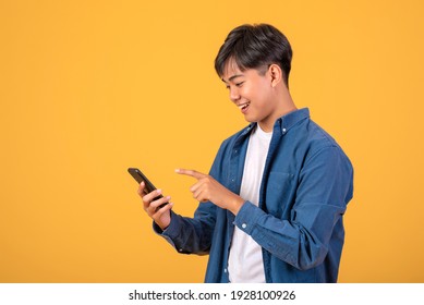 Image Asian Man Standing On Orange Background Using A Mobile Phone.
