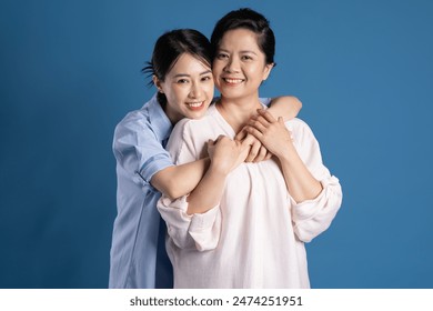 Image of an Asian mother and child posing on a blue background - Powered by Shutterstock