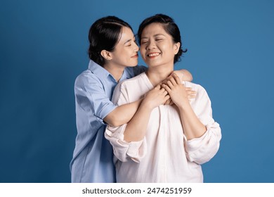 Image of an Asian mother and child posing on a blue background - Powered by Shutterstock