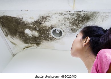 Image Of Asian Woman Looking At The Roof Damage, Caused By Water Leaks