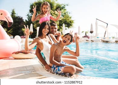 Image Of Attractive Caucasian Family With Children Sitting Near Luxury Swimming Pool With Pink Rubber Ring Outside Hotel