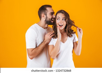 Image of attractive man whispering secret or interesting gossip to woman in her ear isolated over yellow background - Powered by Shutterstock