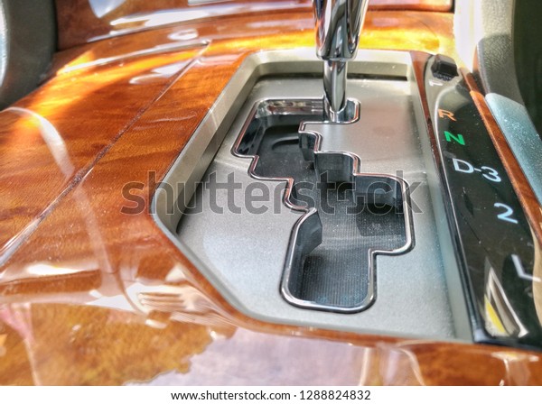 Image of auto\
gear shift with wooden finish panel in cockpit. Focus on gear shirt\
area. Others in gradient\
blur.