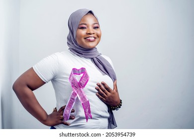 image of beautiful african woman, with head wrap, cheerful black lady with a symbol on her chest, holding one breast- breast cancer awareness concept - Powered by Shutterstock