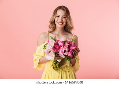 Image of a beautiful amazing young blonde woman posing isolated over pink wall background holding flowers. - Powered by Shutterstock