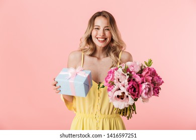 Image Of A Beautiful Amazing Young Blonde Woman Posing Isolated Over Pink Wall Background Holding Flowers Holding Present Gift Box.