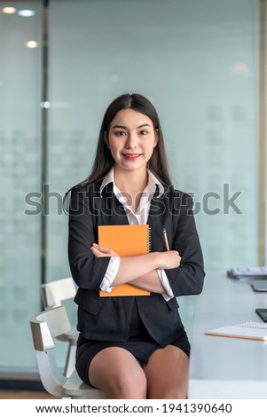 Image of a beautiful Asian businesswoman sitting at the office looking at the camera.