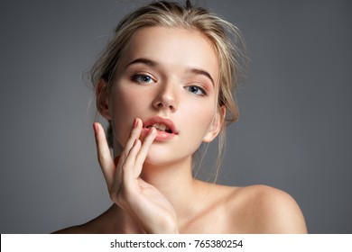 Image With Beautiful Blonde Girl Touching Her Lips On Grey Background. Beauty & Skin Care Concept