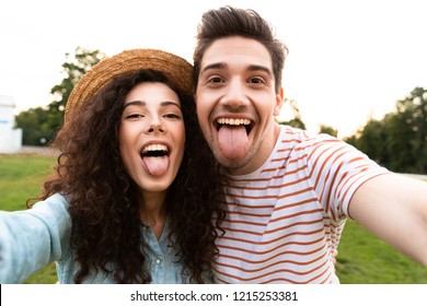 Image of beautiful couple man and woman 20s walking in green park and taking selfie on cell phone - Shutterstock ID 1215253381