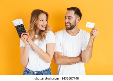 Image Of Beautiful Couple Rejoicing While Holding Credit Card And Passport With Travel Tickets Isolated Over Yellow Background