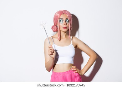 Image Of Beautiful Female With Pink Wig And Bright Makeup, Holding Magic Wand, Cosplay Fairy For Halloween Party, Standing Over White Background