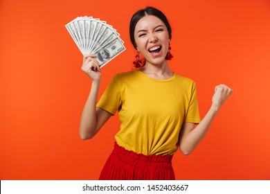 Image Of Beautiful Hispanic Woman 20s Dressed In Skirt Smiling While Holding Bunch Of Money Bills Isolated Over Red Background