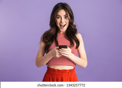 Image Of Beautiful Shocked Excited Young Pretty Woman Posing Isolated Over Purple Background Wall Using Mobile Phone.