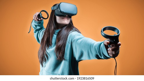 Image of a beautiful stylish woman wearing VR glasses and holding joysticks. Virtual reality concept. Mixed media - Powered by Shutterstock