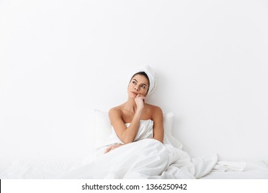 Image Of A Beautiful Thinking Serious Amazing Woman With Towel On Head Lies In Bed Under Blanket Isolated Over White Wall Background.